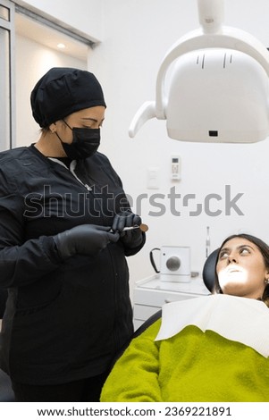 Patient with light on face speaks to Latina dentist woman.