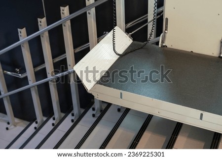 a stair lift for the disabled, wheel chair lift for stairs. Mechanical chair lift taking disabled or aged people up and down stairs. Royalty-Free Stock Photo #2369225301