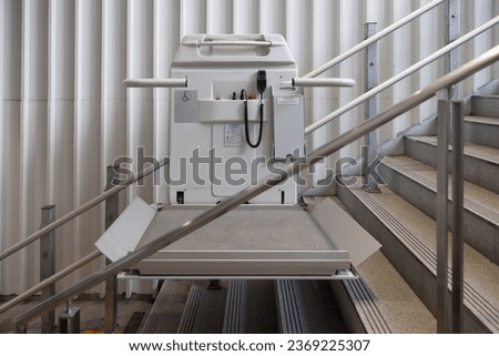 a stair lift for the disabled, wheel chair lift for stairs. Mechanical chair lift taking disabled or aged people up and down stairs. Royalty-Free Stock Photo #2369225307