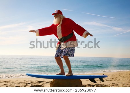 Santa Claus practices his Surfing Skills on his Surf Board on the beach, before he goes into the ocean. Santa Loves the Beach when on vacation from delivering gifts to good boys and girls at christmas