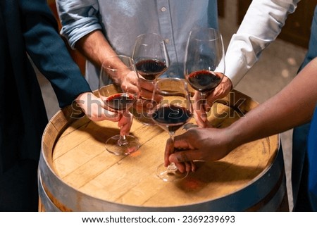 Group of Professional sommelier tasting and smelling red wine in wine glass at wine cellar with wooden barrel in wine factory. Winery liquor manufacturing industry and winemaker business concept. Royalty-Free Stock Photo #2369239693