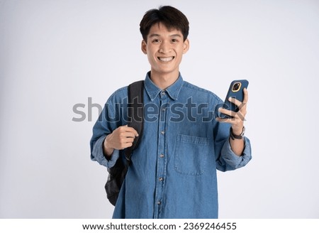 Portrait of Asian male student using phone on white background