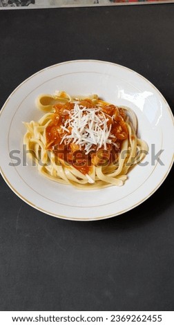 a picture of a plate of spaghetti noodles topped with spices and a sprinkling of grated cheese 