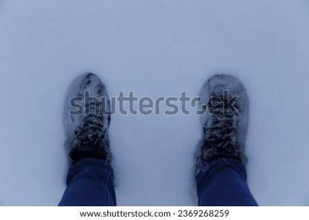 Top view of feet standing in deep snow. Winter hiking boots in snow. First person point of view. Girl taking selfie picture of his shoes