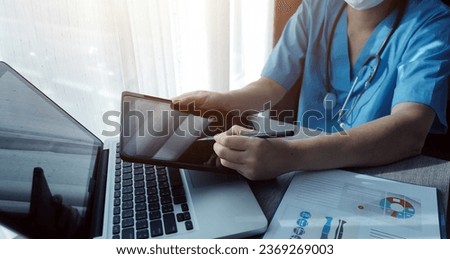 Doctor's working on laptop computer, writing prescription clipboard with record information paper folders on desk in hospital or clinic, Healthcare and medical concept. Focus on stethoscope