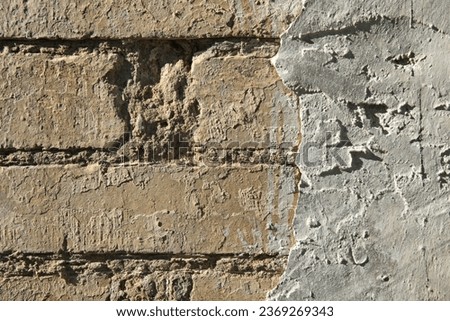 Rough, uneven surface. Cement plaster on a brick wall, texture, background. Old, sloppy, careless brickwork of a house wall. Ancient backdrop of yellowed color. Contrasting view of wall cladding