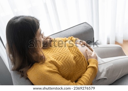 Pregnant asian woman holds hands on belly touching her baby caring about her health Beautiful happy pregnant woman tender mood photo of pregnancy.