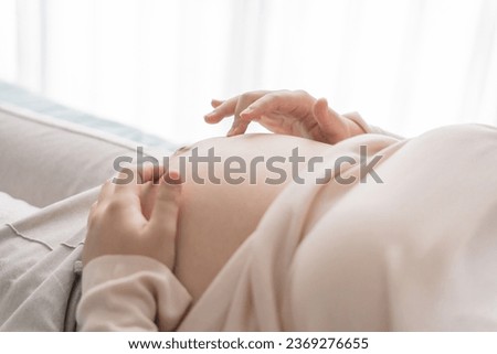 Pregnant woman holds hands on belly touching her baby caring about her health Beautiful happy pregnant woman 
tender mood photo of pregnancy.
