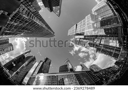 Black and white image looking up at tall, glass skyscrapers in Moscow with a fisheye lens; concept image of modern, urban life as a background
