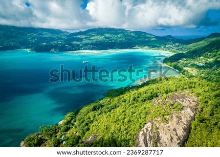 Landscape on a tropical island. Granite rocks, turquoise ocean water, tropical forest. Typical landscape on Mahe island, Seychelles. Natural landscape, vacation picture, travel banner
