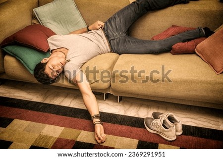 Photo of a young and handsome man resting in a strange position on the floor with a pillow under his head, maybe drunk or very tired Royalty-Free Stock Photo #2369291951