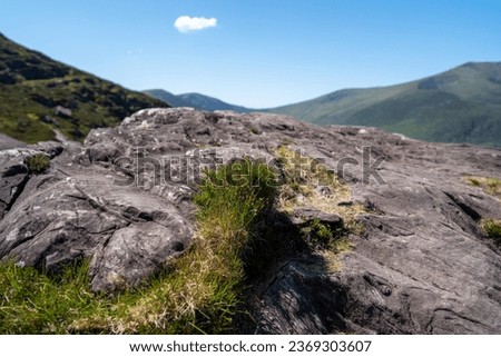 Rocky foreground, mountain background in remote Conor Pass on the Dingle Peninsula on the Wild Atlantic Way in Country Kerry Ireland.  Shot bear loughdoon, peddlers lake,  clogharee, cloughane.   Royalty-Free Stock Photo #2369303607