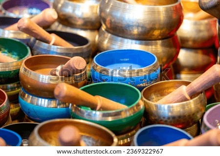 Many small singing bowls mti mallet, in different colors and partly with gold rim, partly stacked Royalty-Free Stock Photo #2369322967