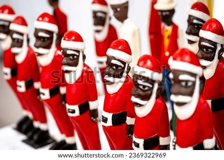 Many identical santas with red suits and black skin color in a row