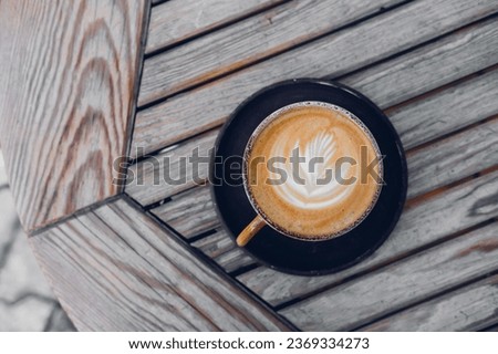 Top view on stylish latte coffee mug with flower art on wooden table background . High quality photo