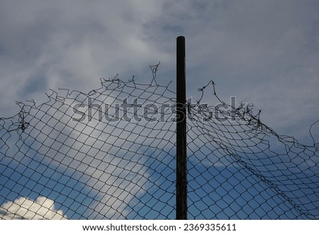 Looking up at a chain link fence with blue sky and clouds. wire fence. Chain link fence see sky. Opening in metallic fence. blue sky. Challenge. breakthrough concept                                   