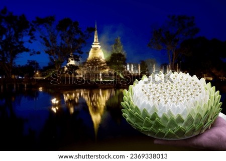 Man's hand holds petal krathong in hand to float in the Loy Krathong Festival at the sukhothai historical park blurred image in night time, Thailand.