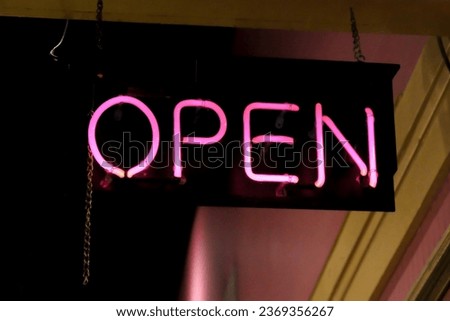 Open sign in pink neon hanging in a business window