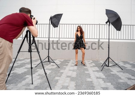 Man taking photo of beautiful fashion girl outdoors, fashion shoot concept Royalty-Free Stock Photo #2369360185