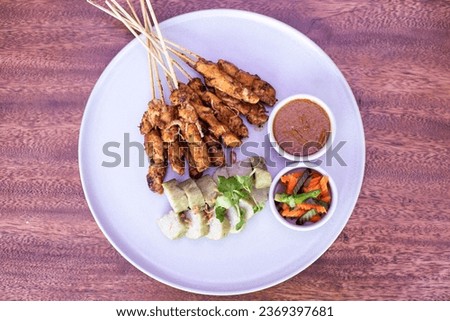 Indonesian food satay with peanut souse, acar and lontong (rice cake) setup on the white plate