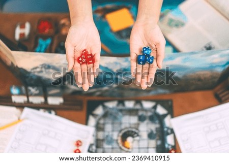 Role playing tabletop game and board games hobby concept. Hand holding blue and red dice for choosing on blur background with adventure story setup ttrpg table.