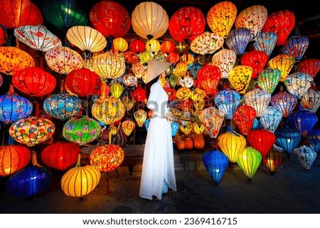 Tourists in traditional Vietnamese clothing look at paper lanterns in Hoi An ancient town. Traditional Vietnamese culture and lanterns at Hoi An ancient city Vietnam Royalty-Free Stock Photo #2369416715