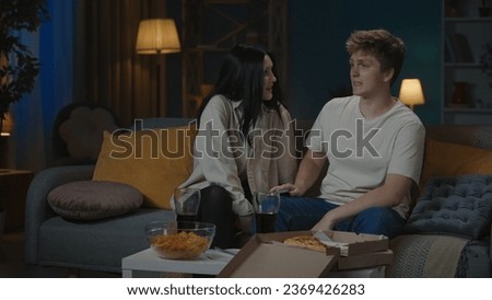 Portrait of teenage couple spending leisure time. Boy and girl sitting on the sofa in the living room and having an argument, angry unhappy face expressions.