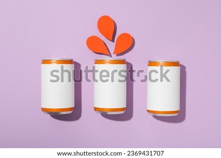 Tin cans and paper drops on purple background, top view