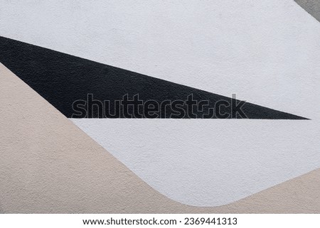 Abstract photo of a wall with a sharp triangular black field around a white and beige colour field.