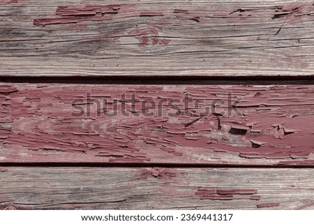 Abstract close-up photo of an old wooden wall with horizontal slats with red peeling paint