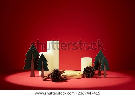 Christmas banner with blank space for presentation product. A round golden tray decorated with dried pine cones, paper plants and scented candles on a red background Royalty-Free Stock Photo #2369447415