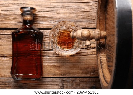 Glass and bottle of whiskey with wooden barrel on table, flat lay