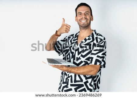 Beautiful attractive Young handsome man wearing printed shirt hold netbook hand finger show thumb up