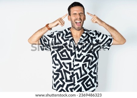 Photo of crazy Young handsome man wearing printed shirt screaming and pointing with fingers at hair closed eyes