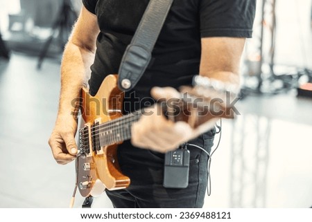 Guitarists play at a rock or rock n roll concert. A guitarist plays chords on an electric guitar.