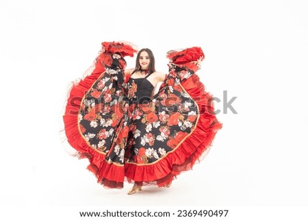 A young girl demonstrates a smart elegant red dress. Flamenco clothing. Gypsy romale style. Professional dancer isolated on white background. Royalty-Free Stock Photo #2369490497