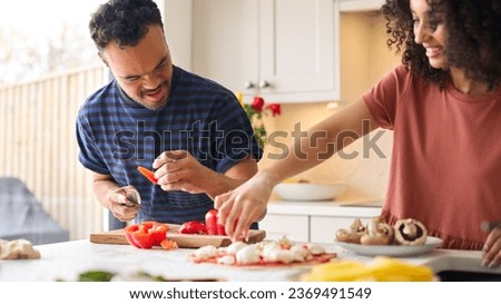 Couple At Home With Man With Down Syndrome And Woman Preparing Topping For Pizza In Kitchen Together Royalty-Free Stock Photo #2369491549