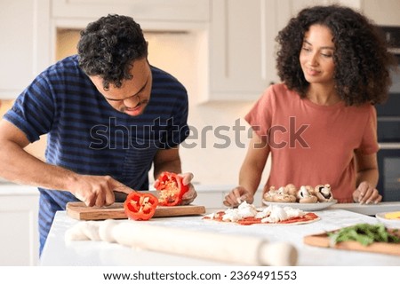 Couple At Home With Man With Down Syndrome And Woman Preparing Topping For Pizza In Kitchen Together