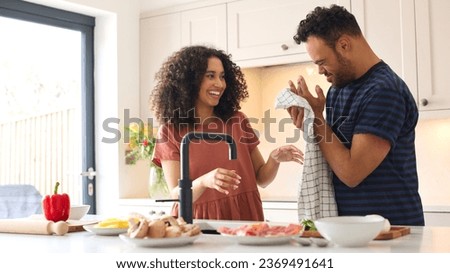 Couple At Home With Man With Down Syndrome And Woman Washing Hands Before Preparing Meal In Kitchen Royalty-Free Stock Photo #2369491641