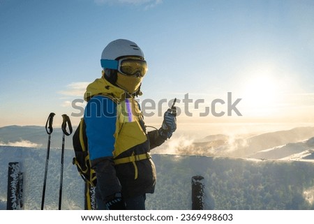 woman skier taking picture of sunset above the mountains
