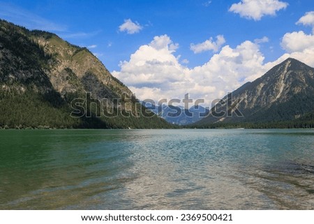 View over the lake Heiterwanger See near Heiterwang in Austria on a sunny day with blue sky and cumulus clouds. Royalty-Free Stock Photo #2369500421