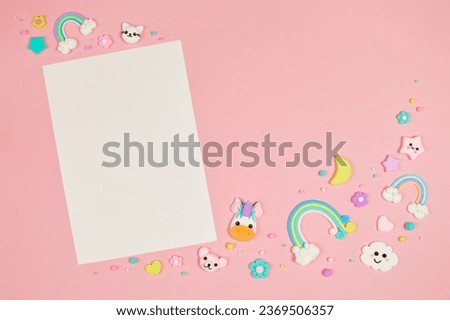 Blank white card on pastel pink background with frame of cute kawaii air plasticine handmade cartoon animals, stars, rainbows. Empty photo frames, baby's photo book, scrapbooking design template Royalty-Free Stock Photo #2369506357