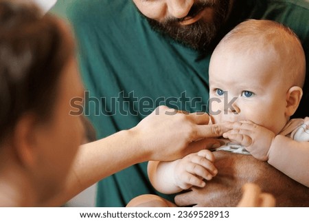 Little boy was happy and biting fingers of mother, climb first teeth. Concept help numbs of gums for baby.