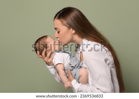 Mother kissing her cute newborn baby on olive background