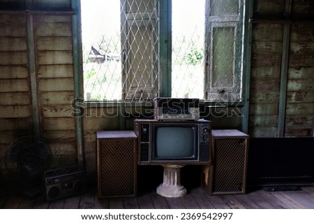 Antique vintage television or old retro  TV on table in living room for thai people use watching televisions program in abandoned building green house or ฺBaan khiao at Phak Hai in Ayutthaya, Thailand