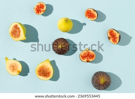 Pattern scene with yellow and black figs on sunny day. Minimal arrangement on blue background. Flat lay.