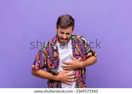 young man feeling anxious, ill, sick and unhappy, suffering a painful stomach ache or flu Royalty-Free Stock Photo #2369571963