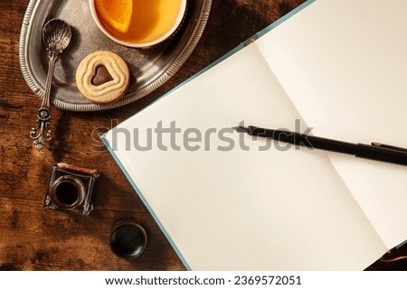 Journal mockup with orange tea and chocolate cookie, with ink and a pen, vintage style, overhead flat lay shot Royalty-Free Stock Photo #2369572051