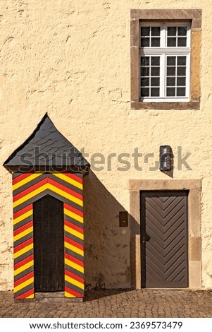 Guardhouse on a yellow house facade at an old castle, with a historic entrance door and wooden windows