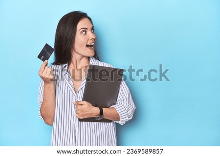 Professional with laptop and credit card on blue